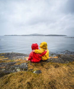children hugging sitting by ocean